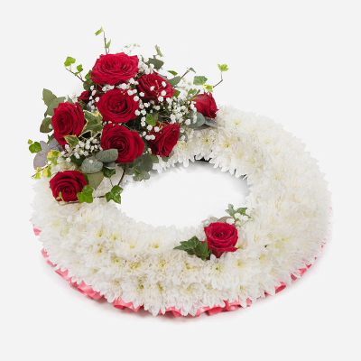 Wreath SYM-314 - White Massed Wreath with Red Rose Spray. A classic arrangement to send for a funeral. Approx size - 35 cm / 14” Oasis Wreath Frame with a Red Ribbon edge.